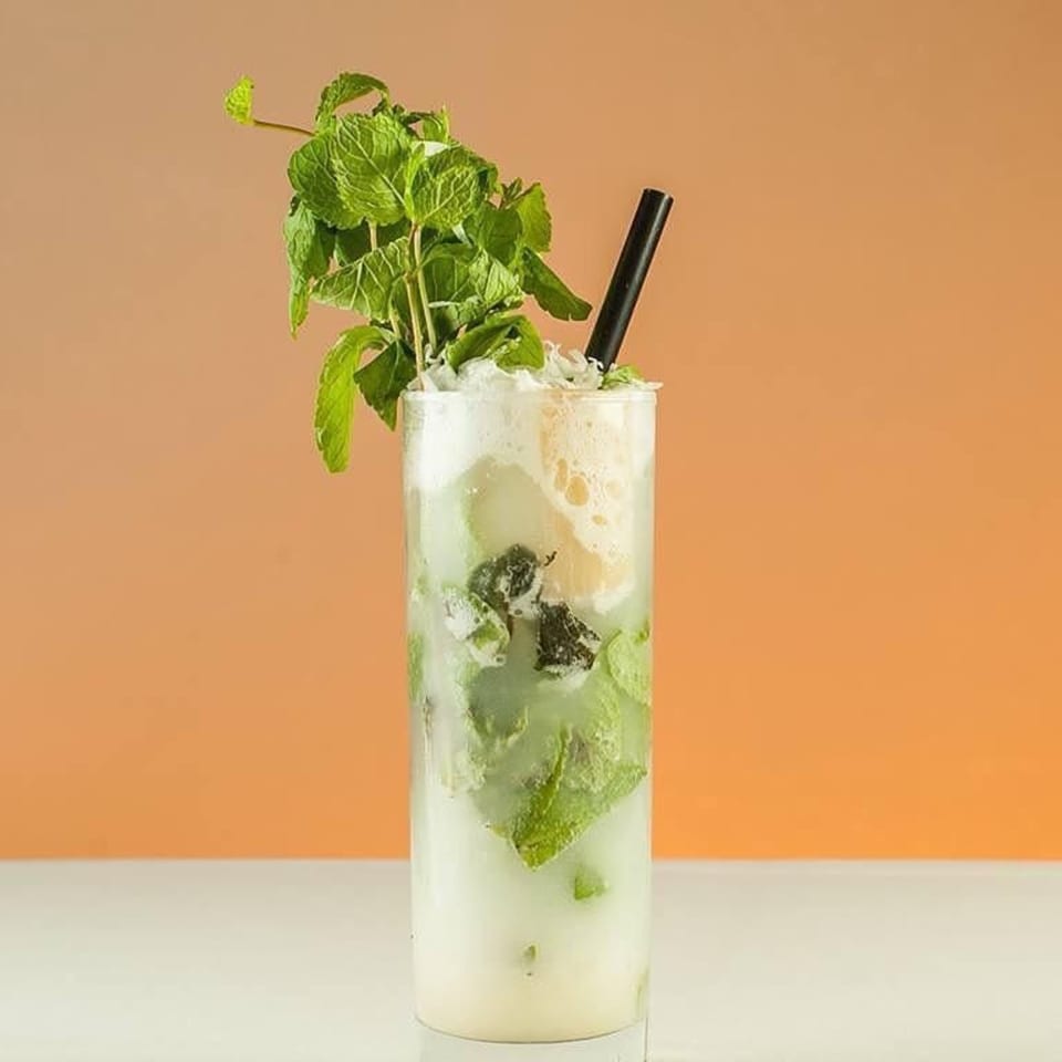 A refreshing mojito cocktail with fresh mint and a black straw, served at Jimmy's Grand Cafe.