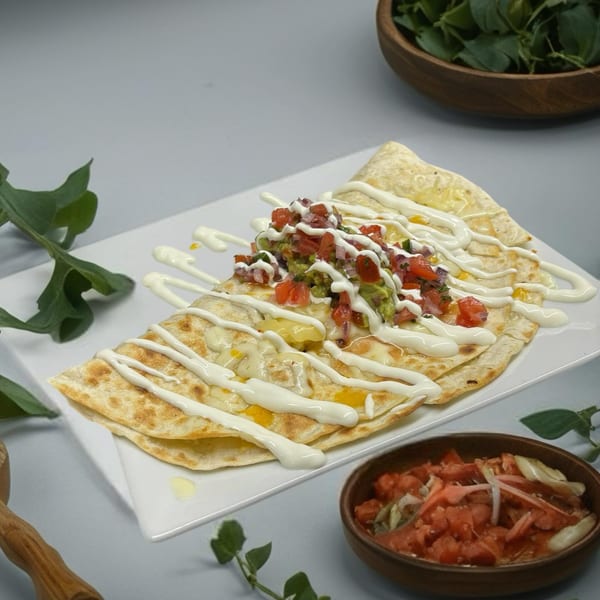Cheesy quesadillas drizzled with sour cream, topped with pico de gallo and guacamole, served at Jimmy's Grand Cafe.