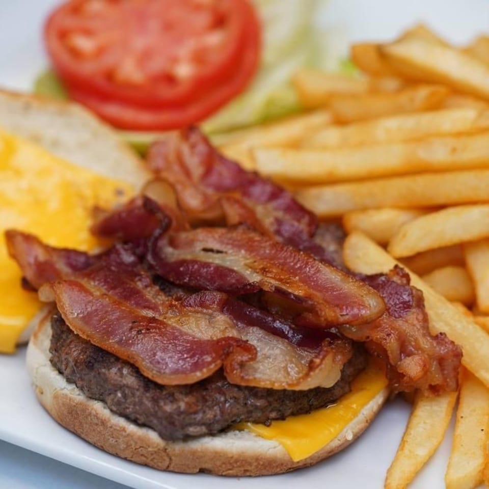 Jimmy's Grand Cafe bacon cheeseburger with fries, lettuce, and tomato on a white plate.